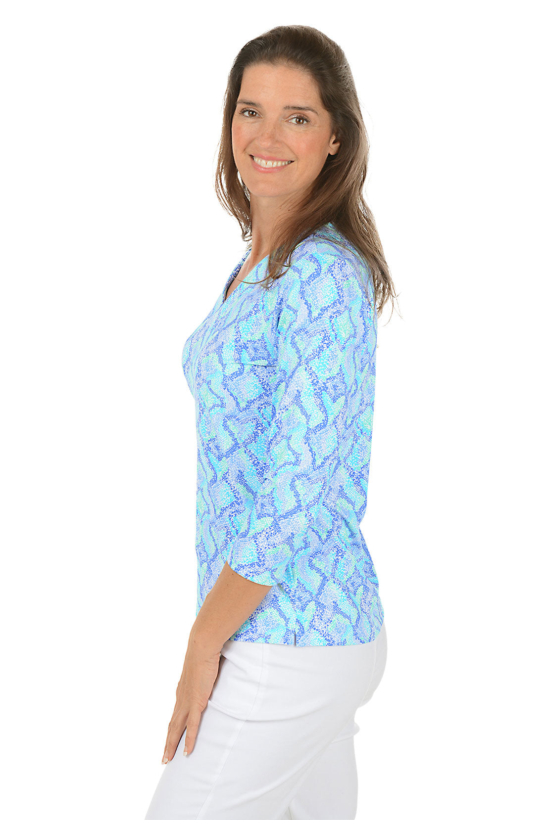Woman wearing a blue patterned top on a white background. Side shot.