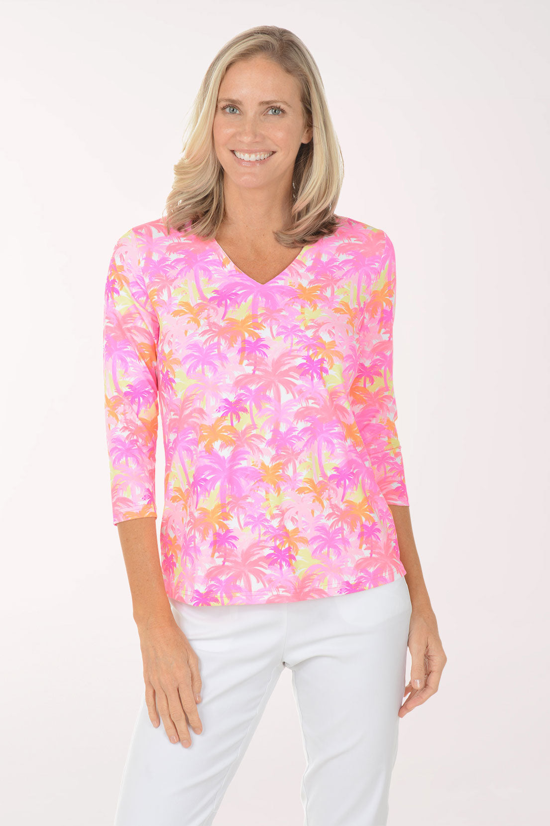 Woman wearing a colorful floral blouse with white pants on a white background