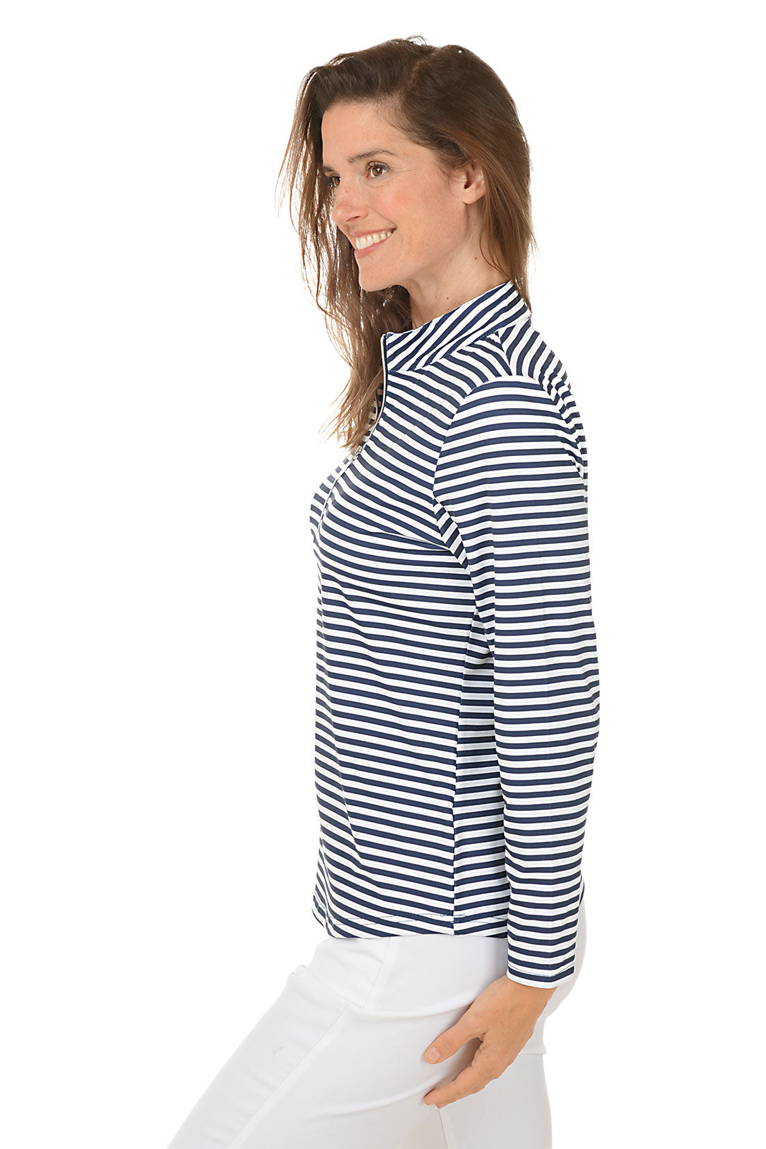 A woman wearing a navy and white striped mock neck long sleeve top with a zippered half placket, paired with white pants. Side shot.