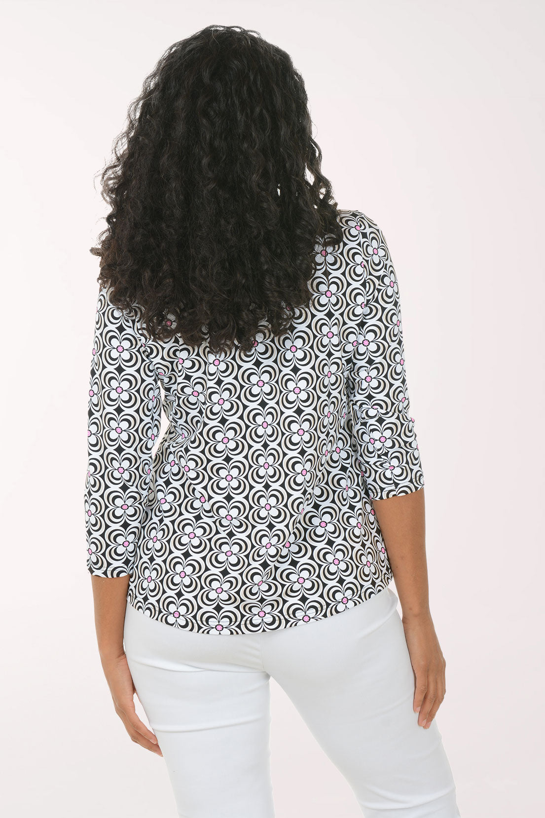 Woman wearing a patterned blouse and white pants on a white background