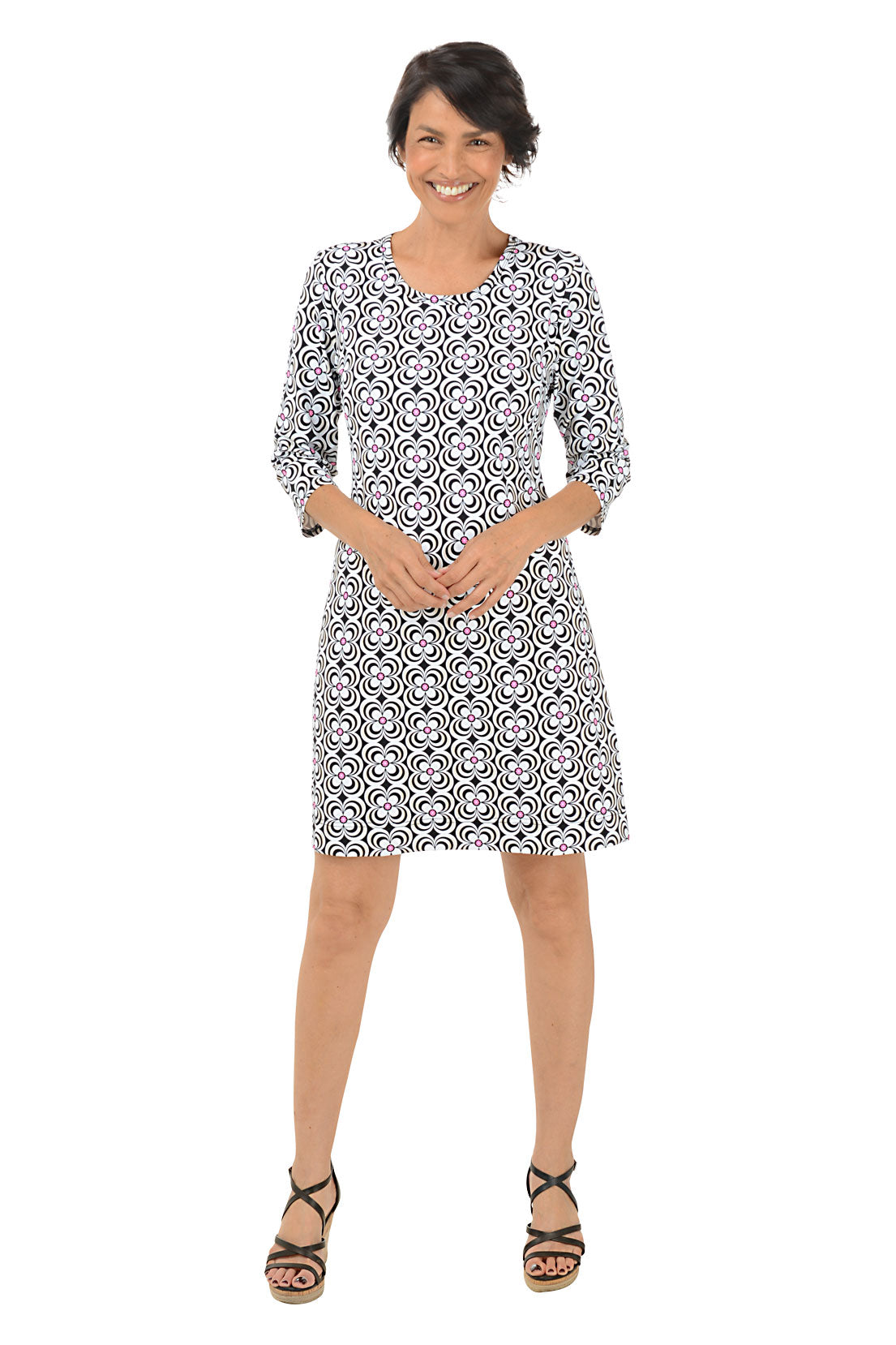 A woman standing and posing in a knee-length floral dress with a scoop neckline and 3/4 sleeves. Front shot.