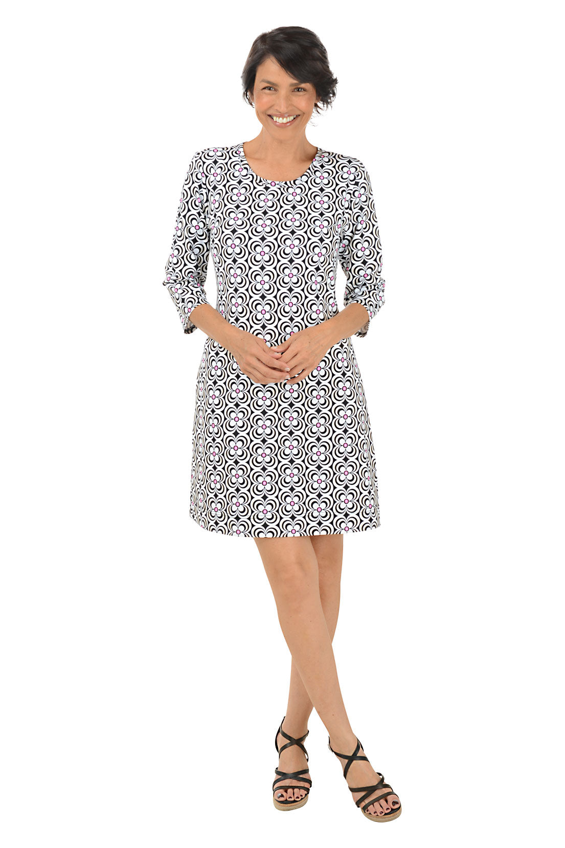 A woman standing and posing in a knee-length floral dress with a scoop neckline and 3/4 sleeves.