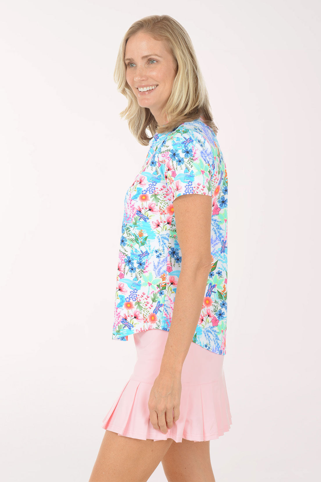 Woman wearing a colorful floral blouse and pink skirt on a white background