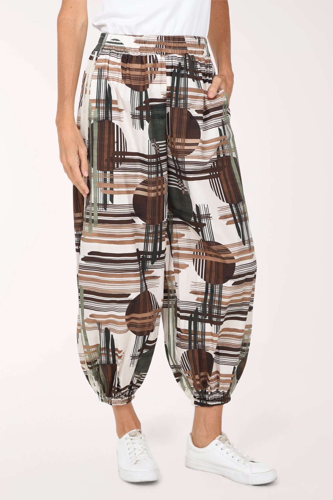 Woman wearing camouflage plaid patterned ankle length joggers with contrast stripes on side leg.