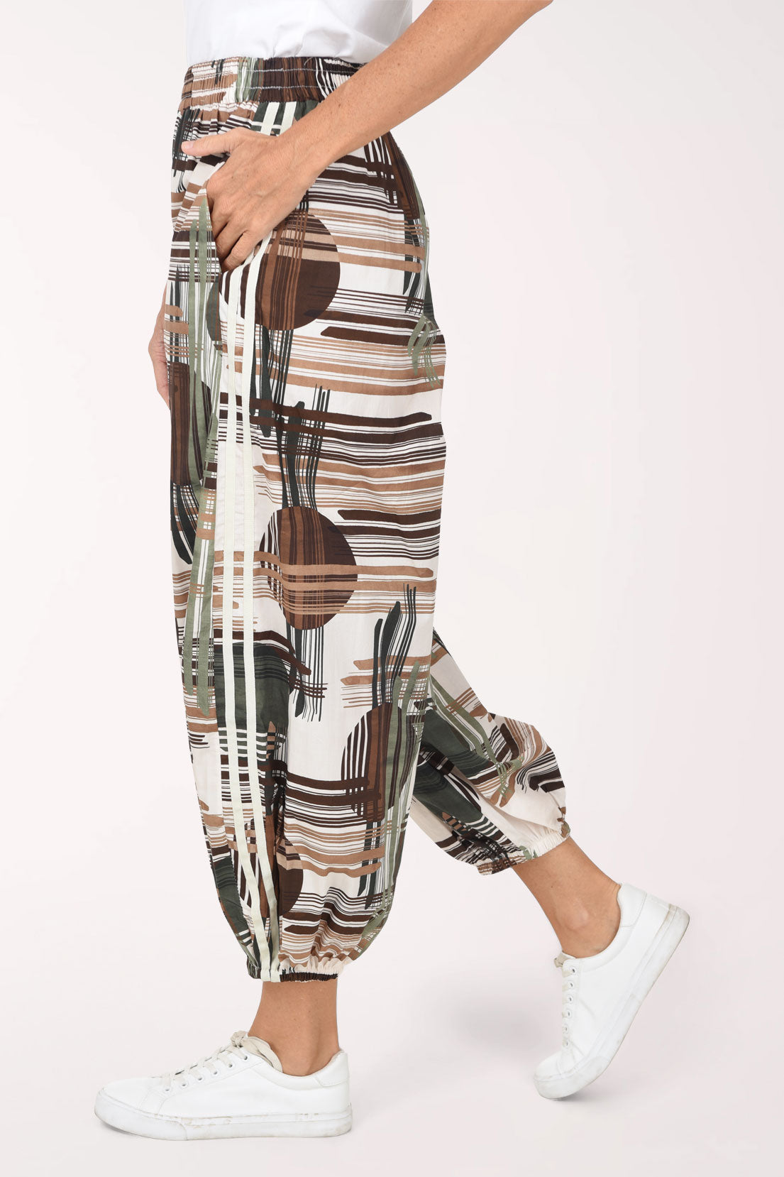 Woman wearing camouflage plaid patterned ankle length joggers with contrast stripes on side leg.