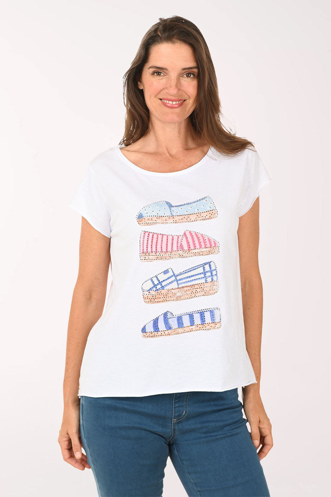 Woman wearing a white t-shirt with shoe designs on a plain background