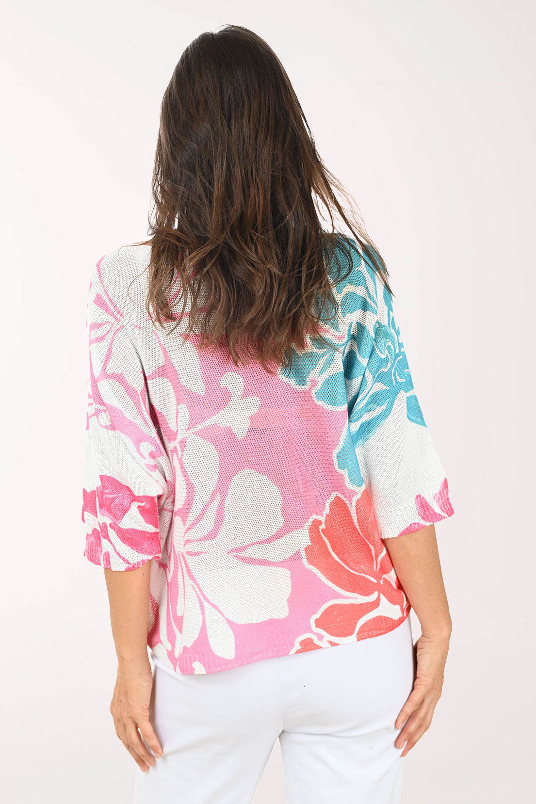 Woman wearing a colorful floral sweater against a white background