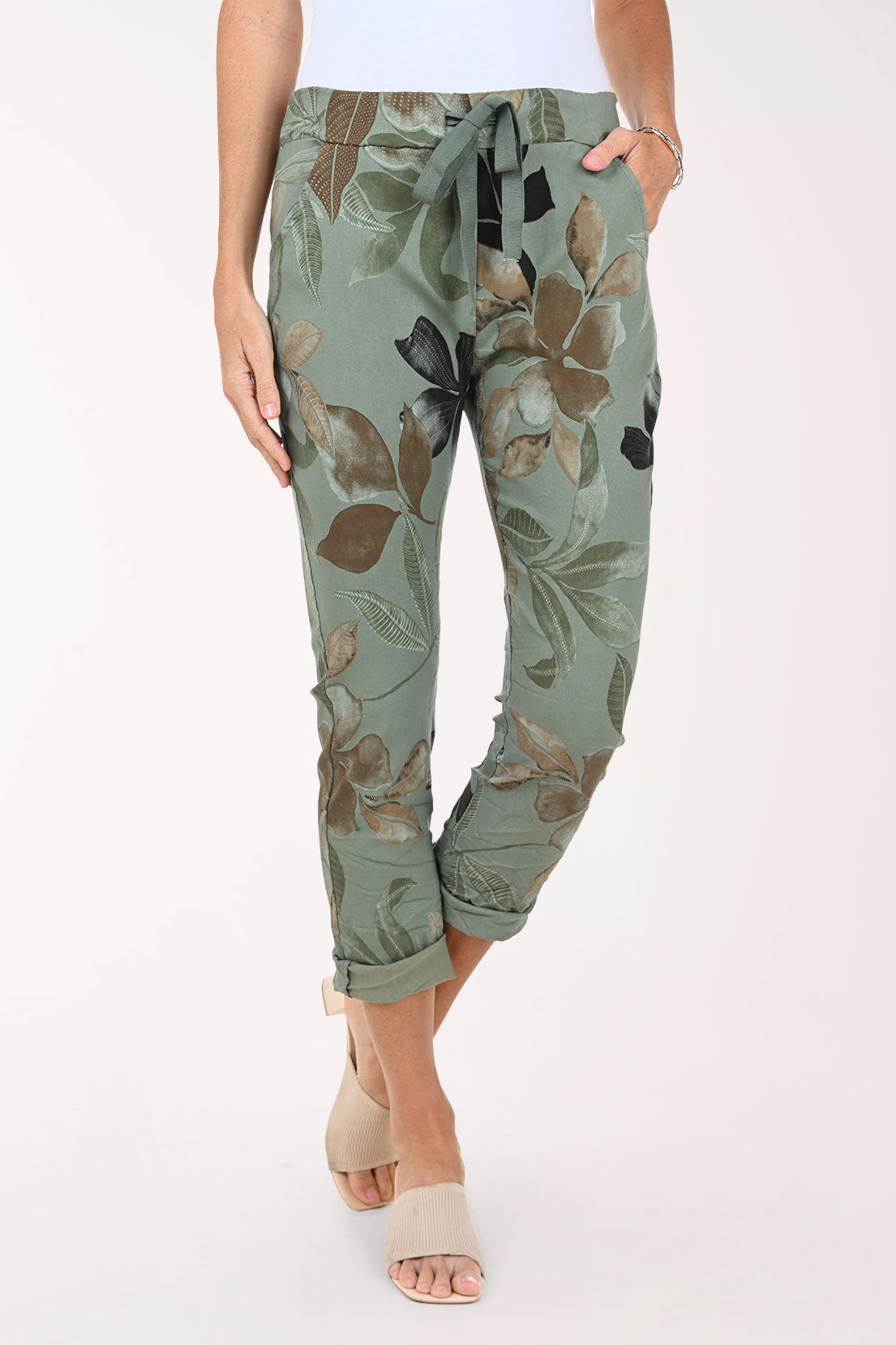 Green floral pants worn by a person on a white background