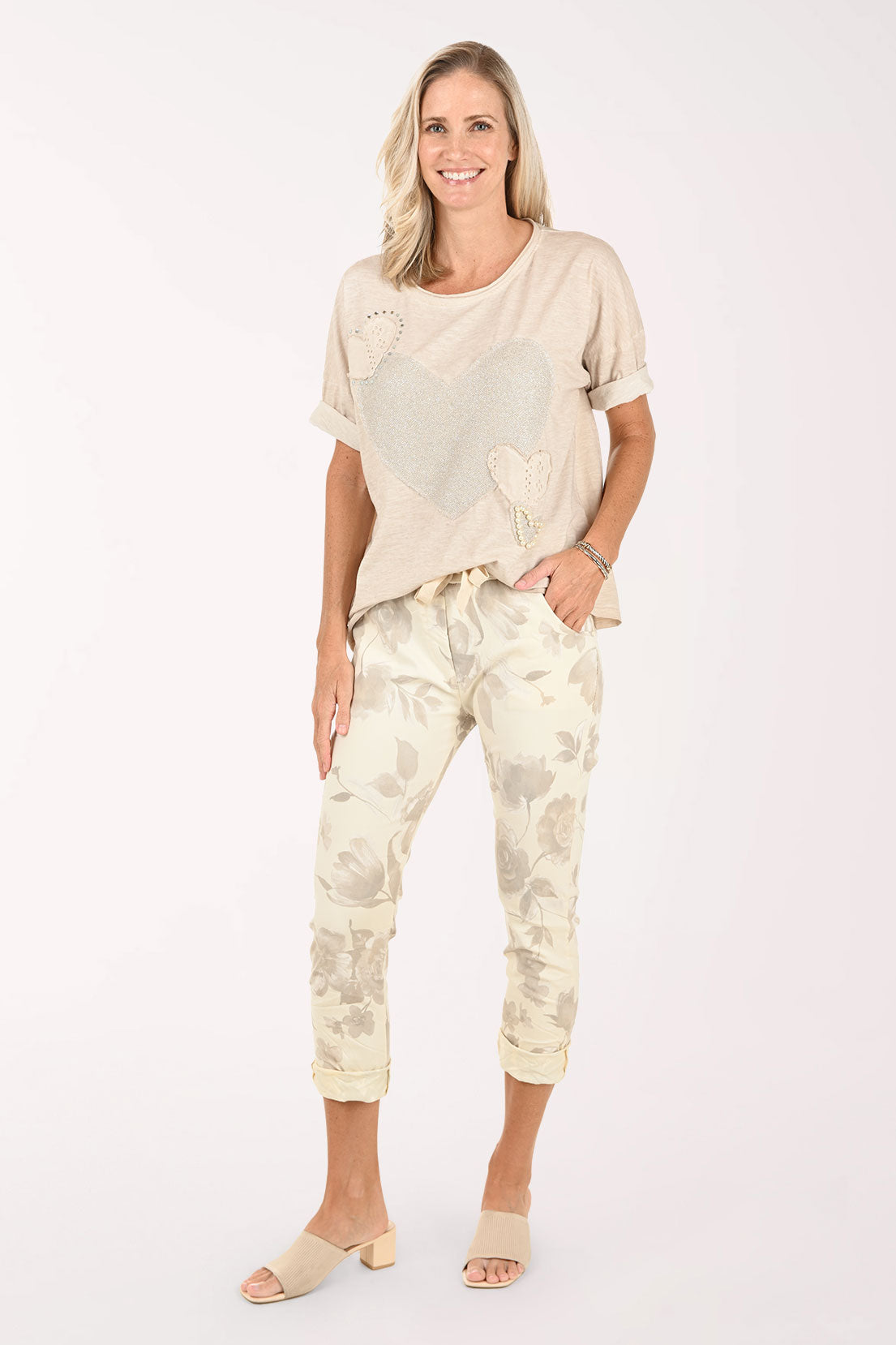 Woman wearing a beige top and patterned pants on a white background