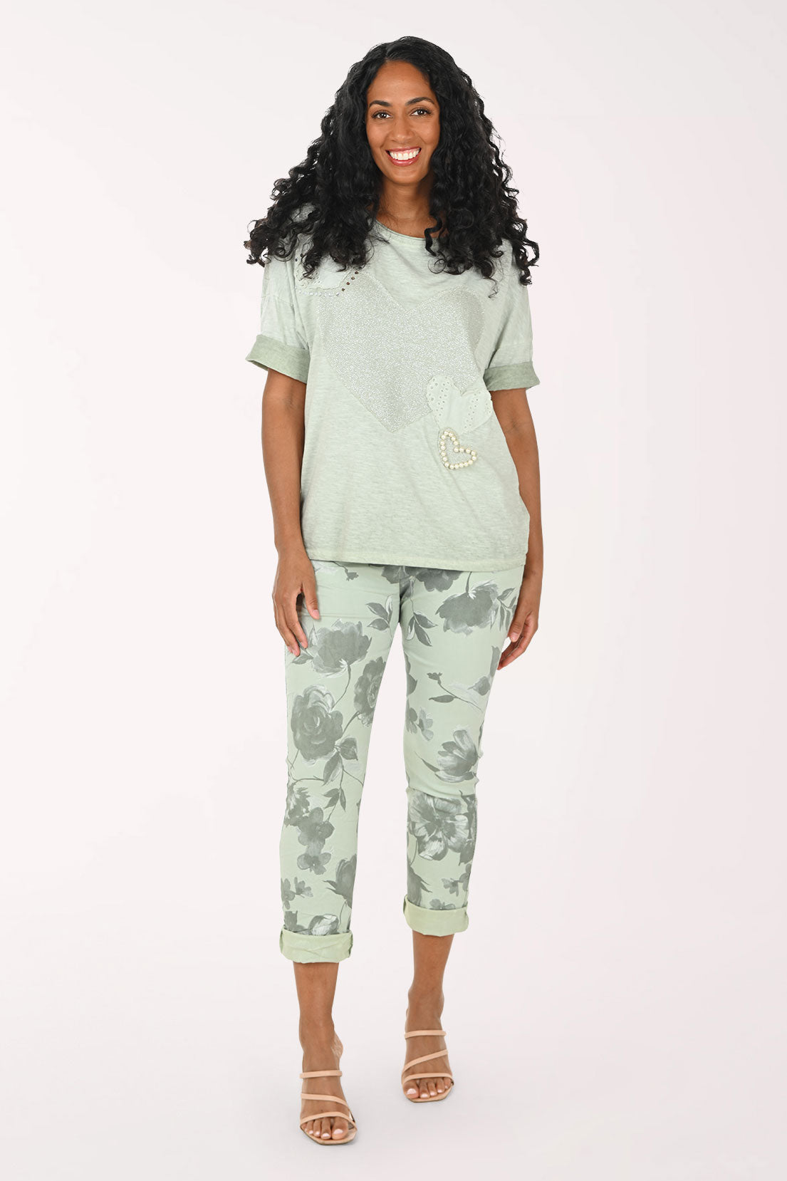 Woman wearing a green jogger set with floral patterns on a white background