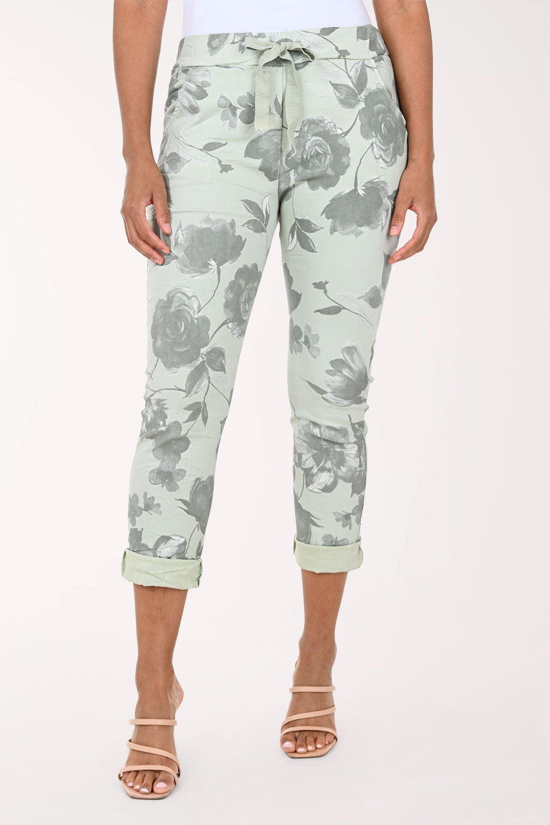 Person wearing light green floral pants on a white background