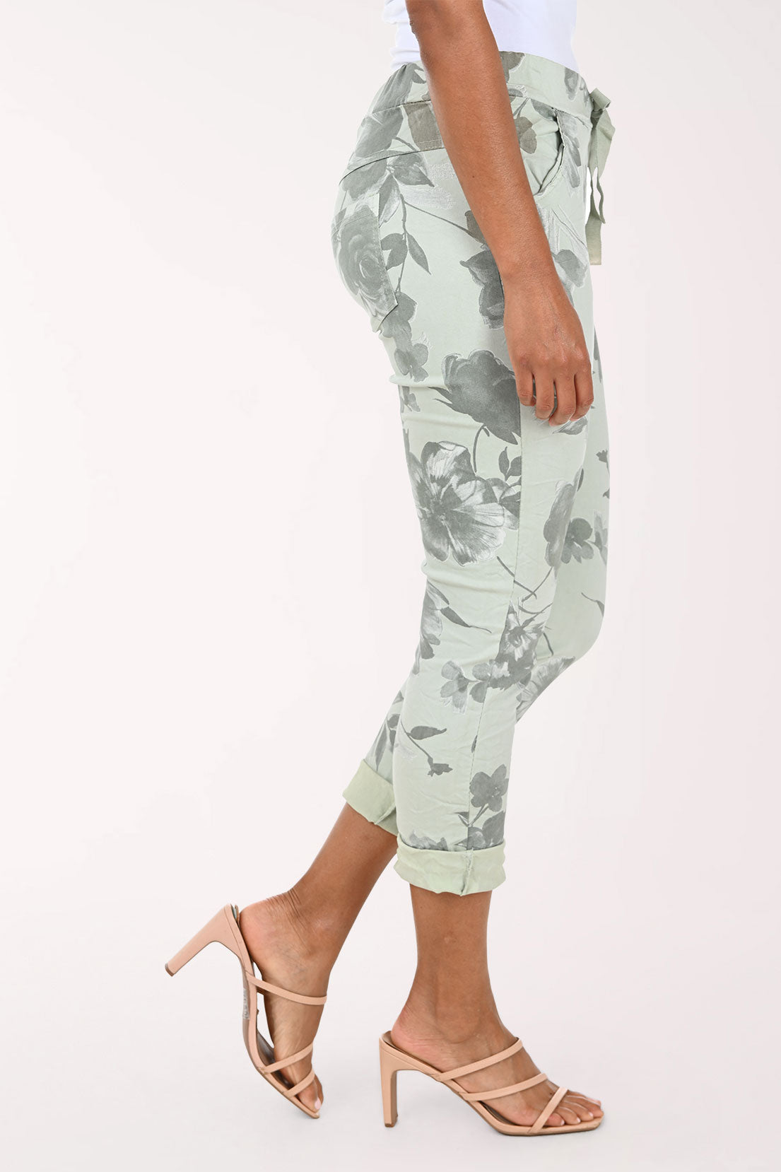 Person wearing light green floral pants on a white background