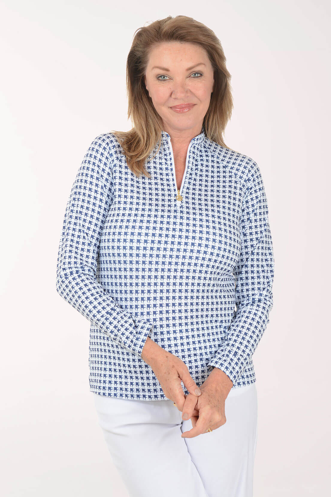 Woman wearing a navy and white patterned long-sleeve quarter-zip top with white pants.