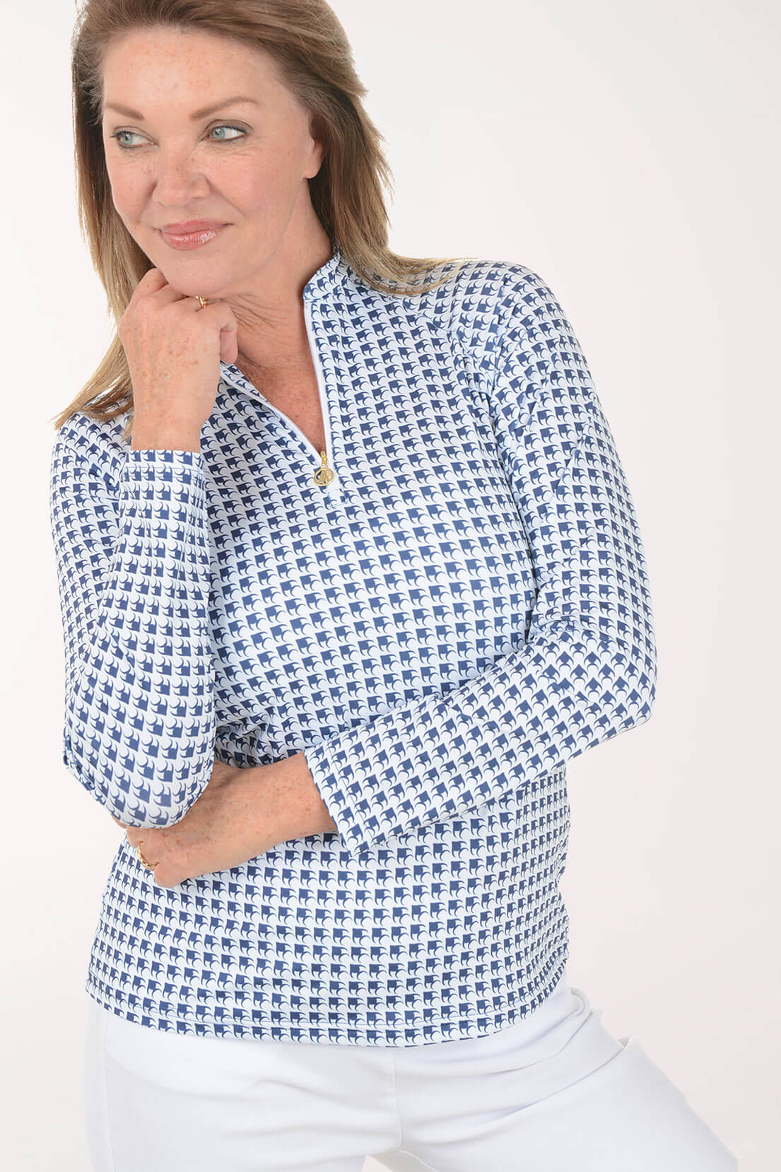 Woman wearing a navy and white patterned long-sleeve quarter-zip top with white pants.