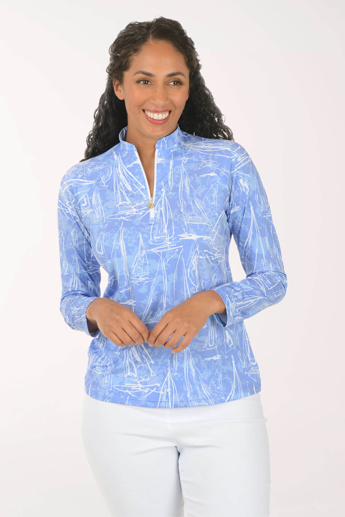 A woman modeling a light blue long-sleeve quarter-zip pullover with an abstract white brushstroke pattern, paired with white pants, against a plain white studio background.