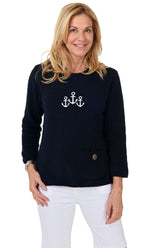 Woman wearing a navy sweater with anchor design on a white background