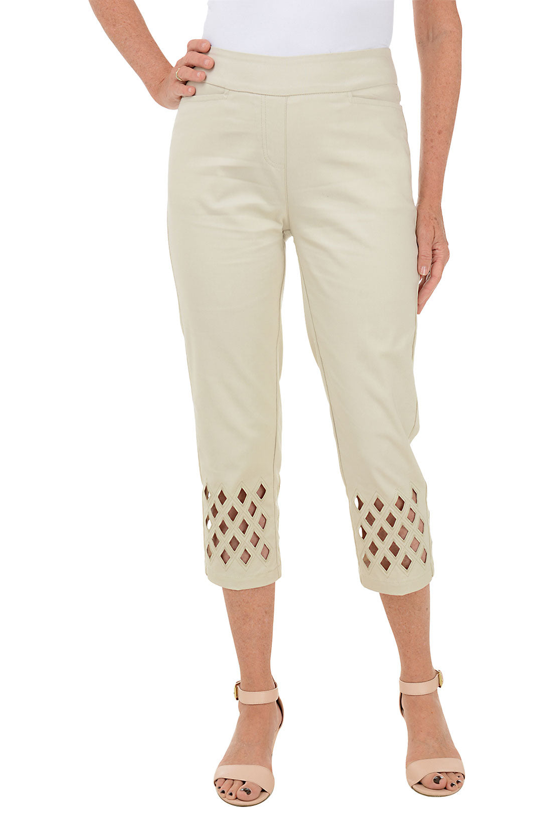 A woman wearing beige cropped trousers with diamond eyelet cut-outs at the hem.