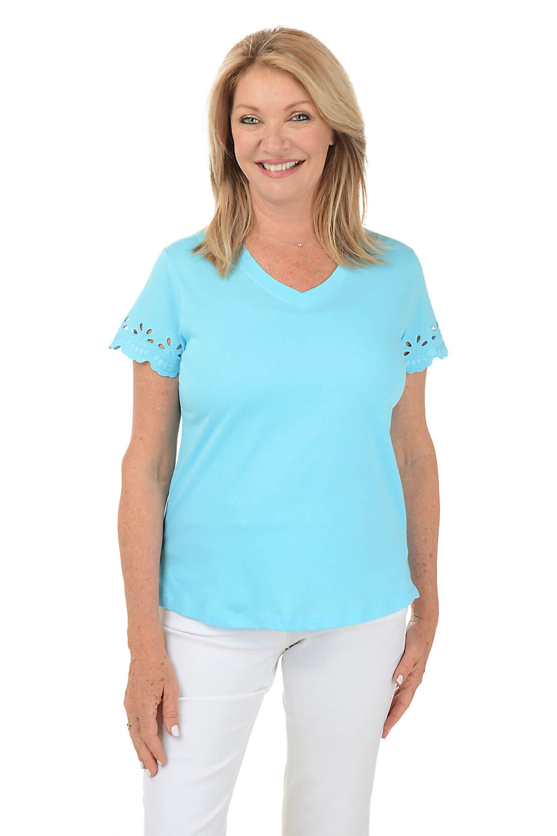A woman wearing a turquoise short-sleeved t-shirt with eyelet scallop detailing on the sleeves, paired with white pants.