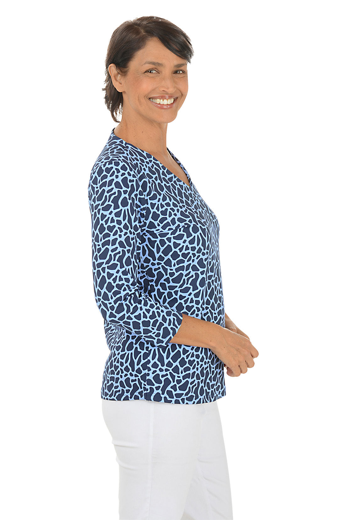 A side view of the navy and light blue giraffe print V-neck top with 3/4 sleeves, worn with white pants.