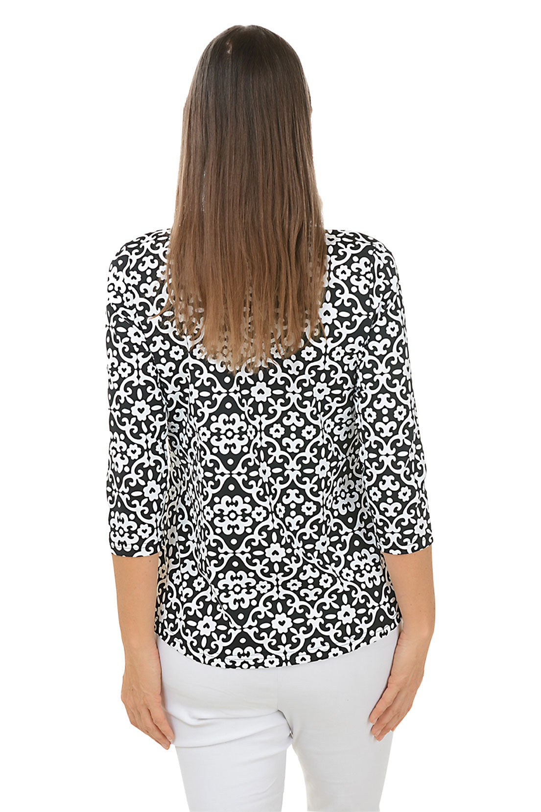 A woman wearing a black and white geometric patterned top with a ruffle neckline and 3/4 sleeves, paired with white pants. Back shot.
