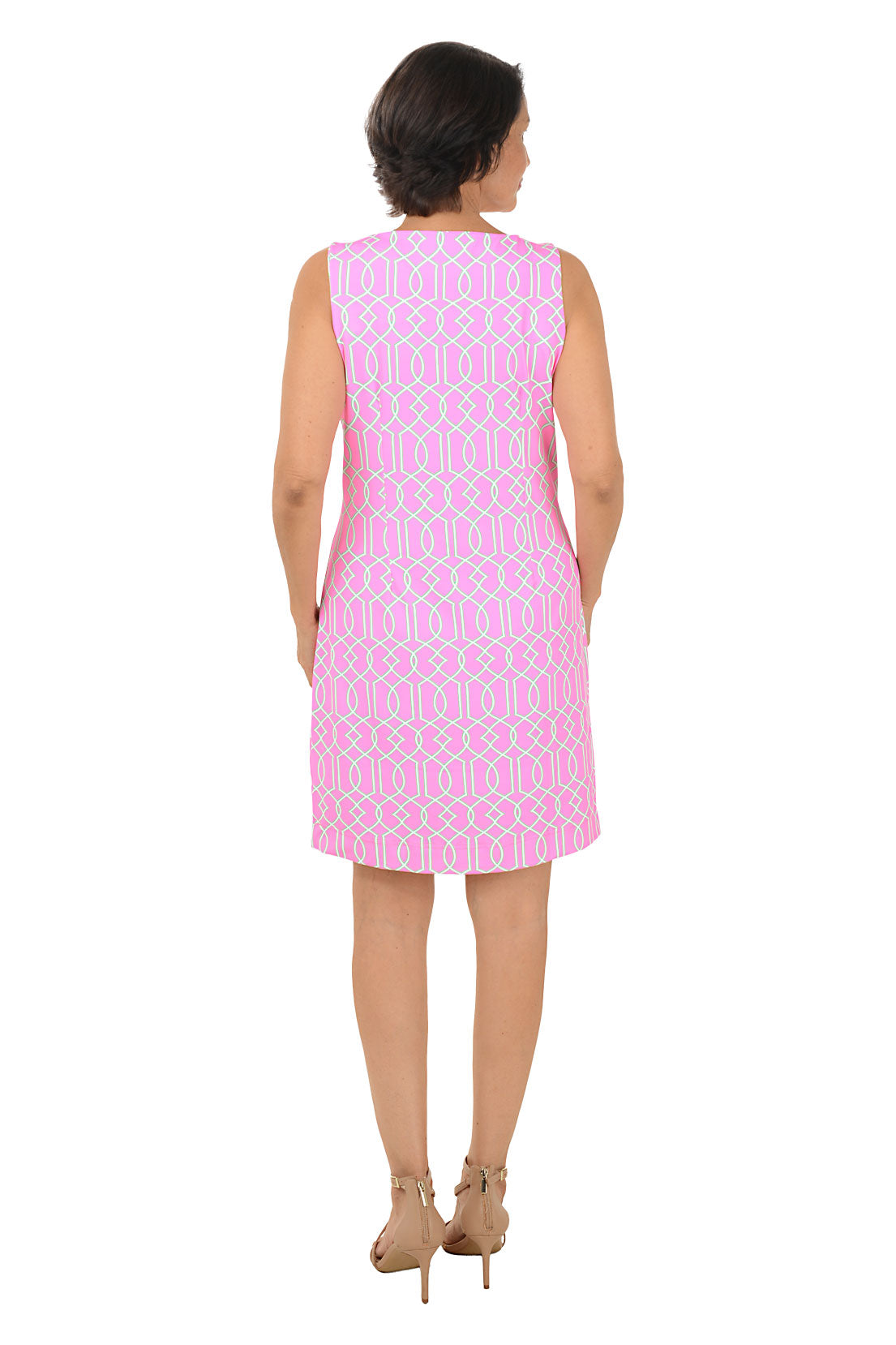 Woman wearing a pink patterned dress on a white background. Back shot.