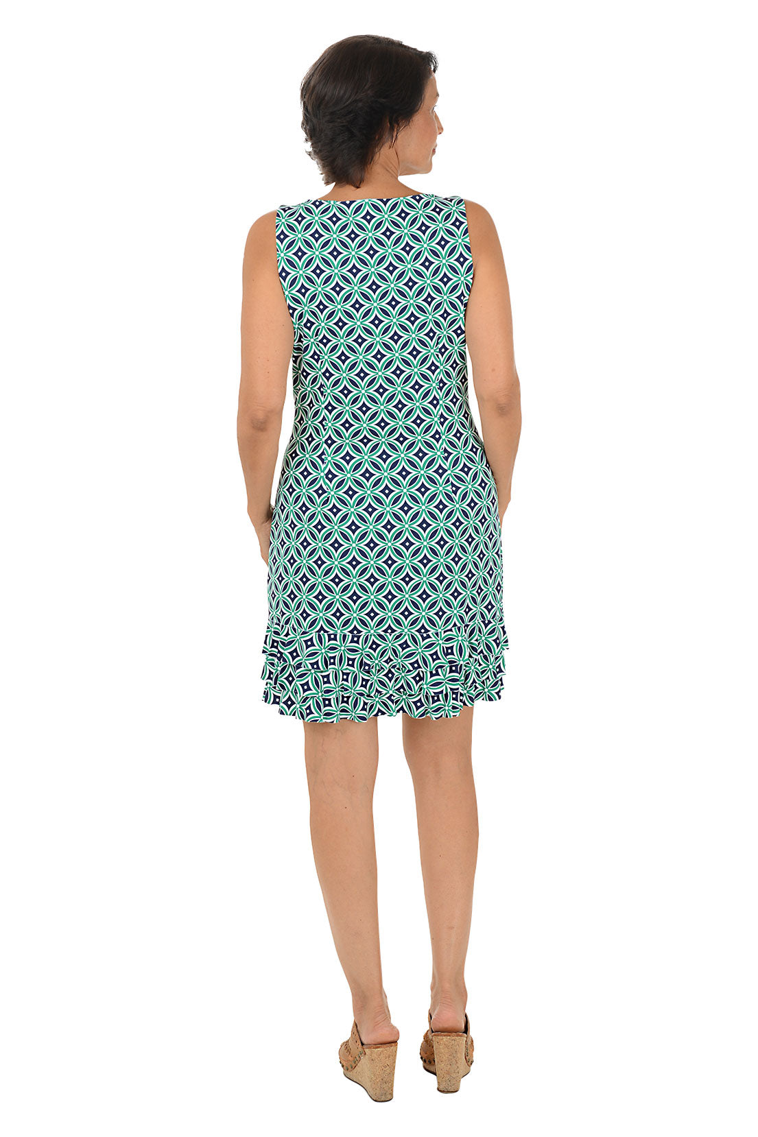 Woman wearing a sleeveless teal patterned dress with a triple ruffled hem on a white background. Back shot.