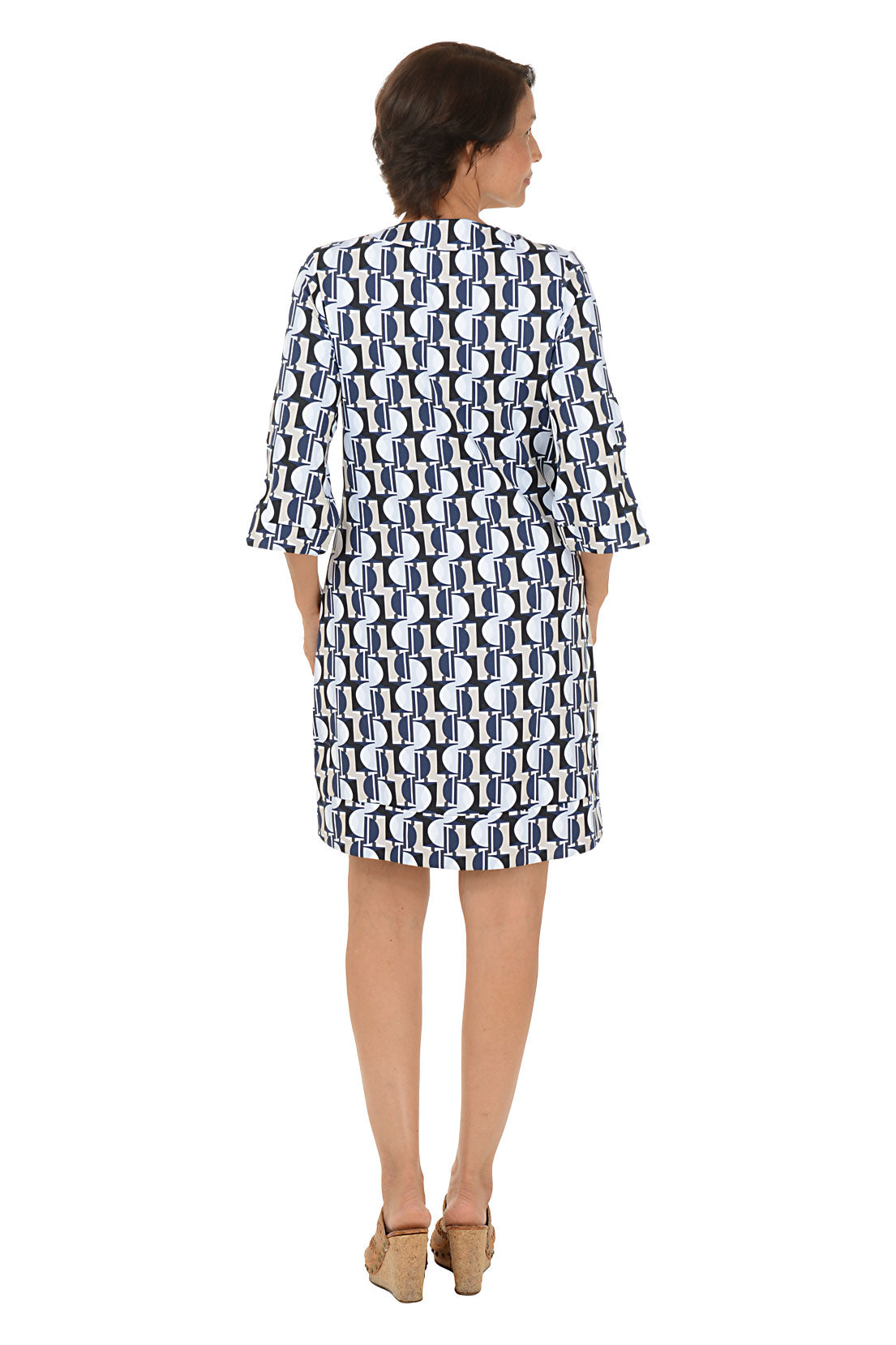 Woman wearing a patterned dress on a white background. Back shot.