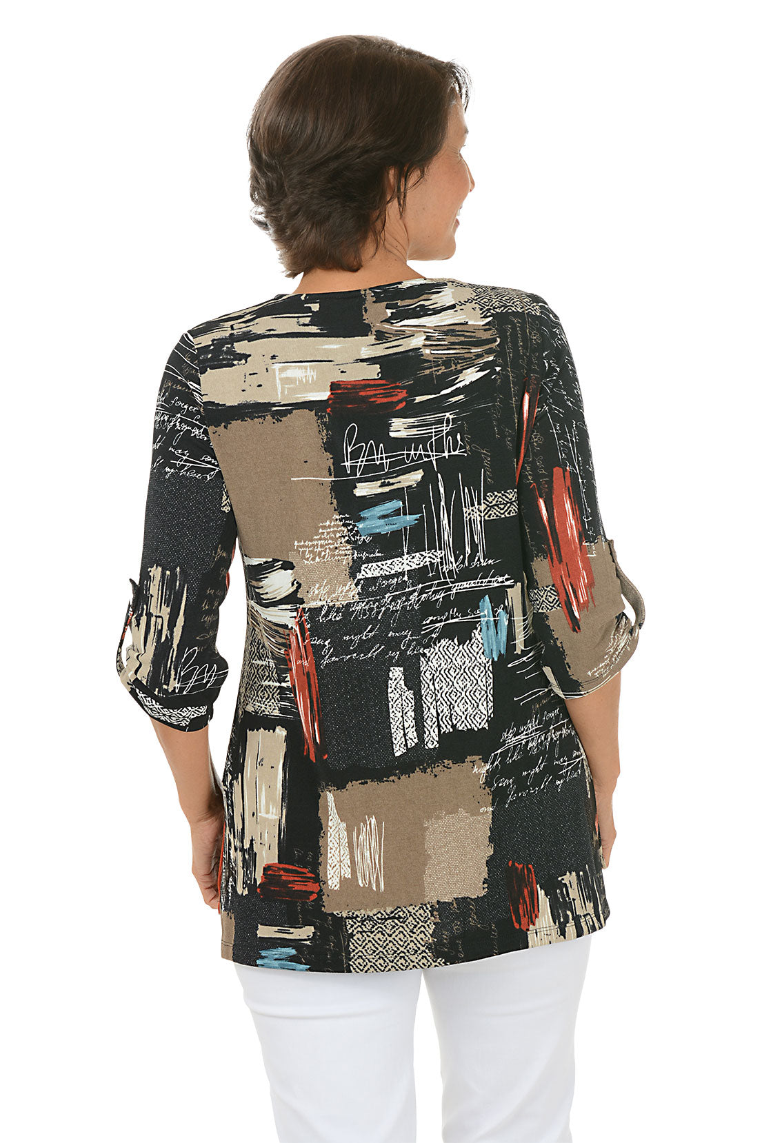 Woman wearing a colorful patterned blouse with white pants on a white background. Back shot.