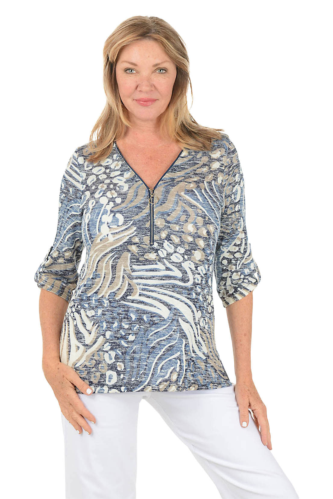 Woman wearing a patterned blouse with white pants on a white background.