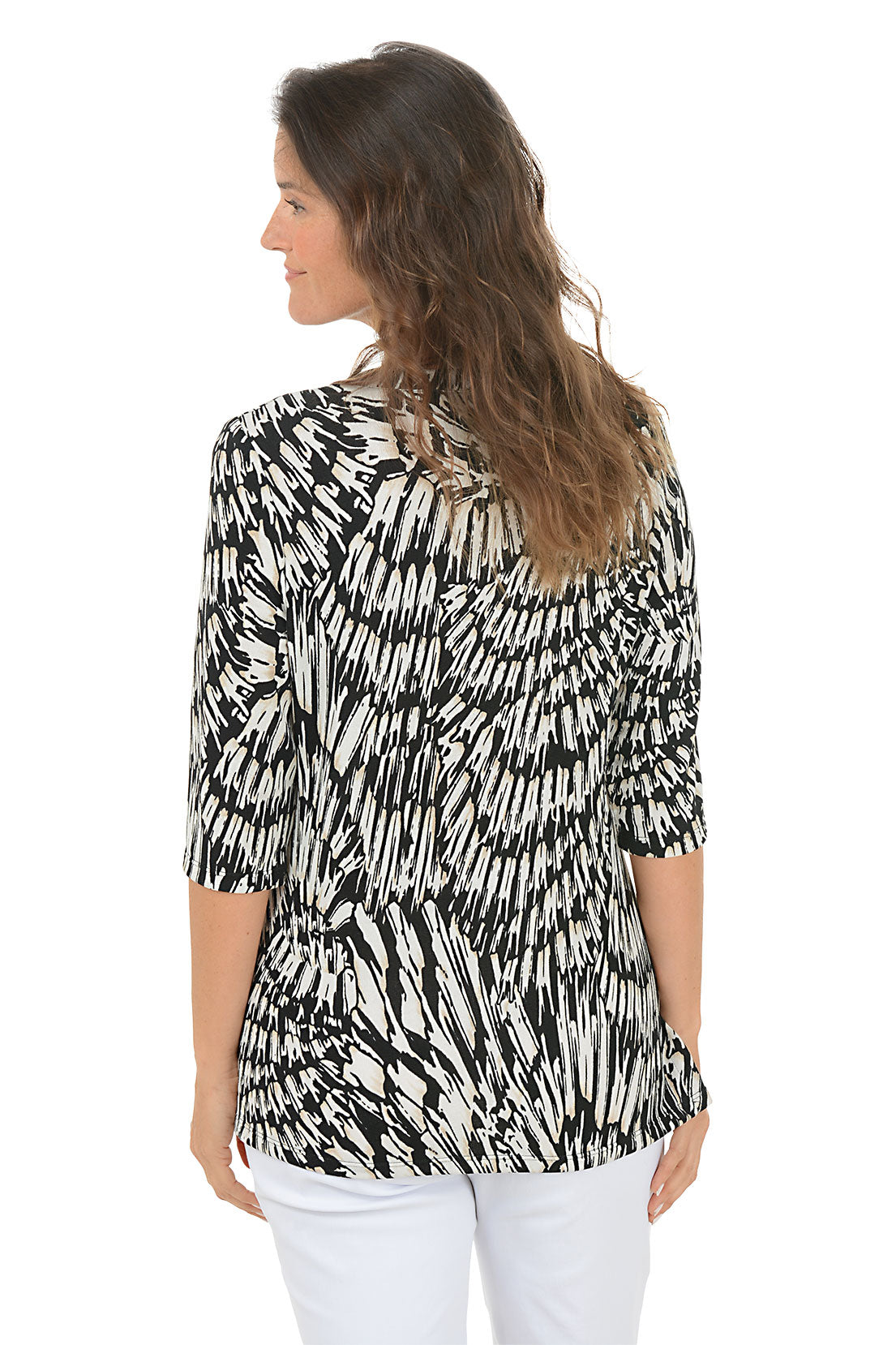 Woman wearing a black and white patterned top with white pants on a white background. Back shot.