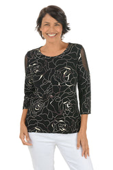 Woman wearing a black floral patterned top on a white background.