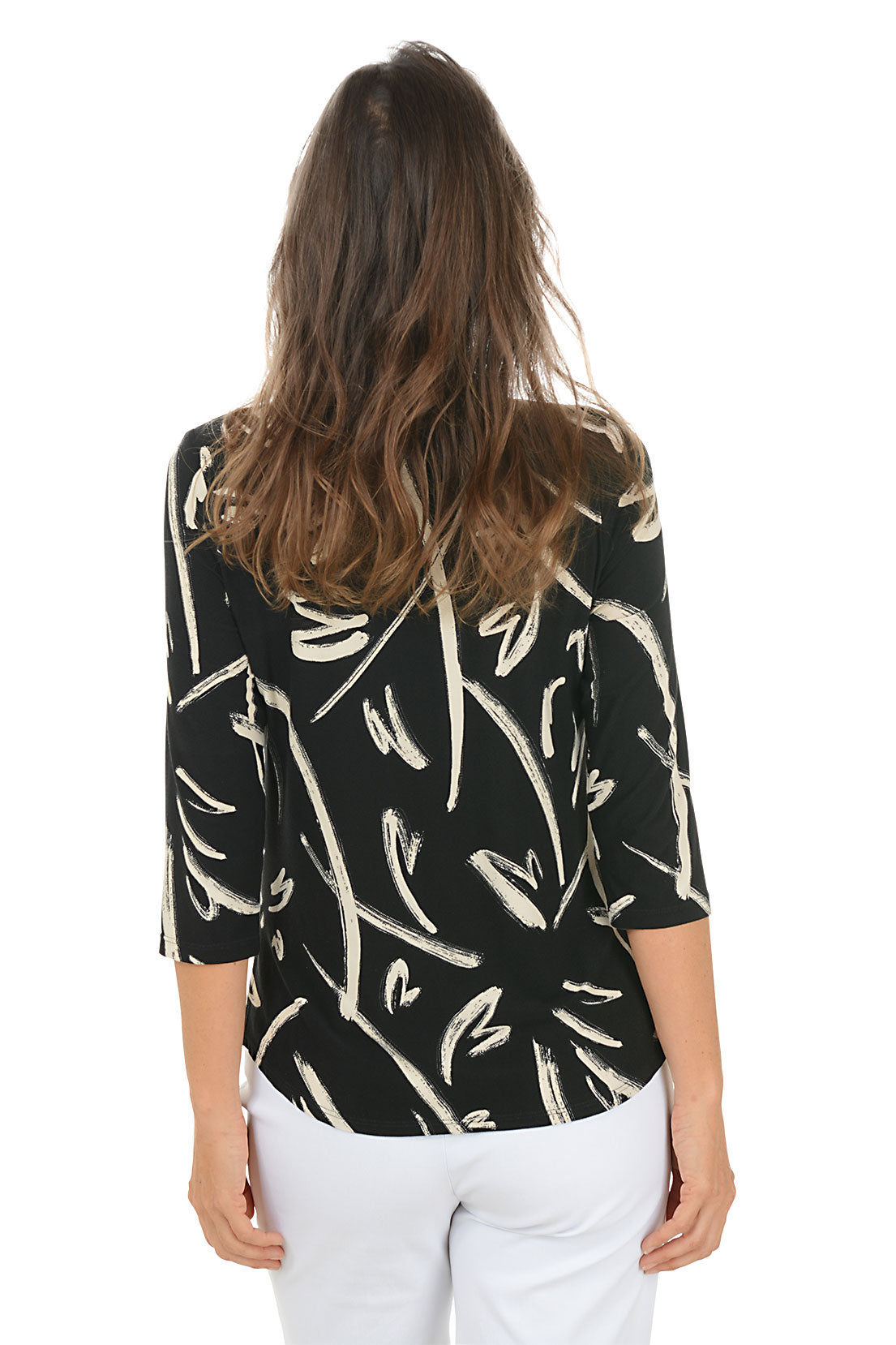 Woman wearing a black and white patterned top with arms crossed on a white background. Back shot.