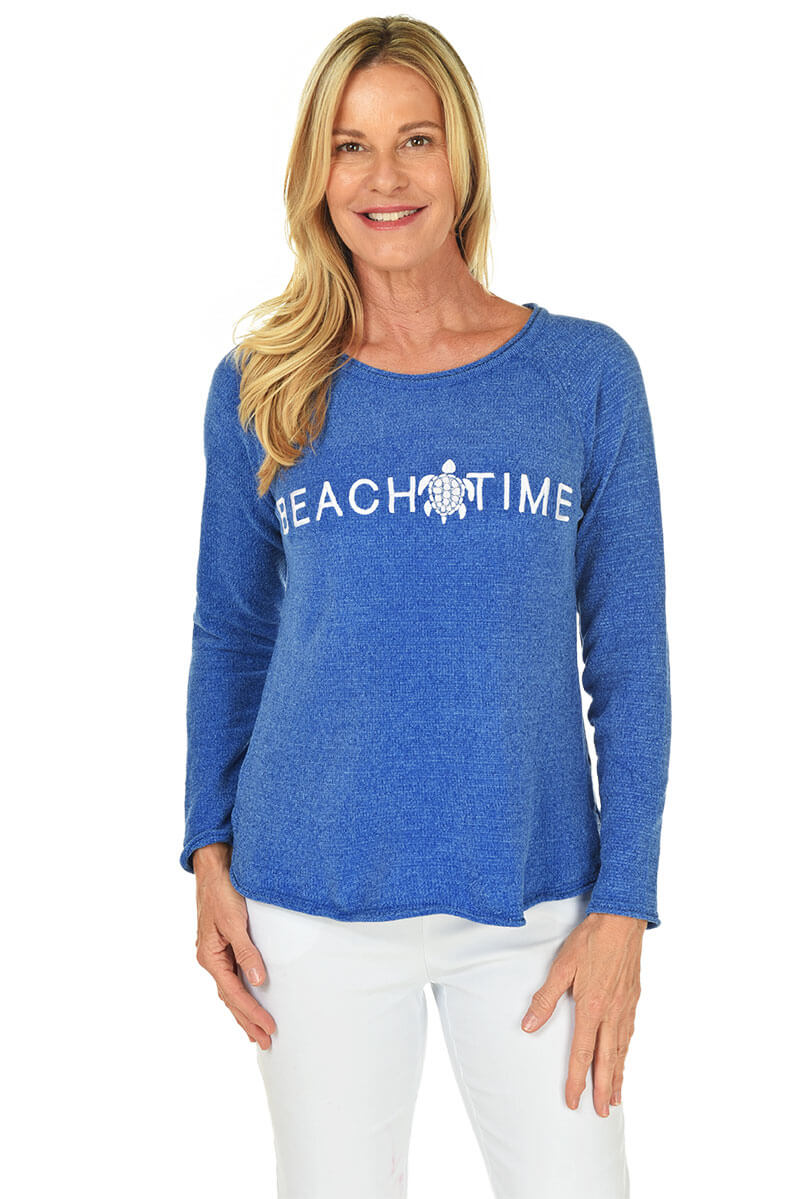 Woman wearing a blue long-sleeve shirt with 'Beach Time' text, standing against a white background