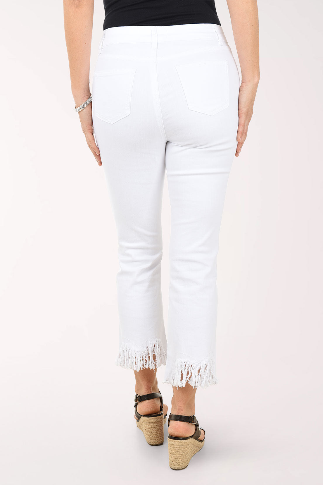 White jeans with frayed hems worn by a person on a white background