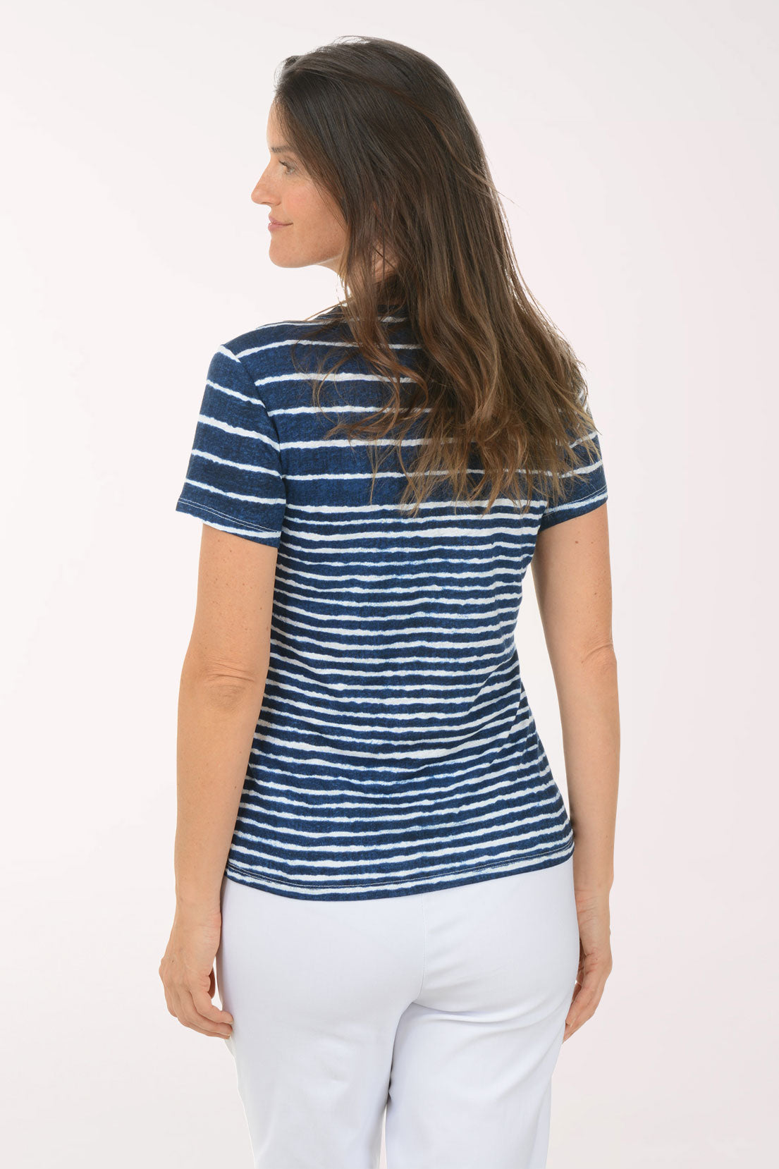 Woman wearing a blue and white striped shirt and white pants on a white background