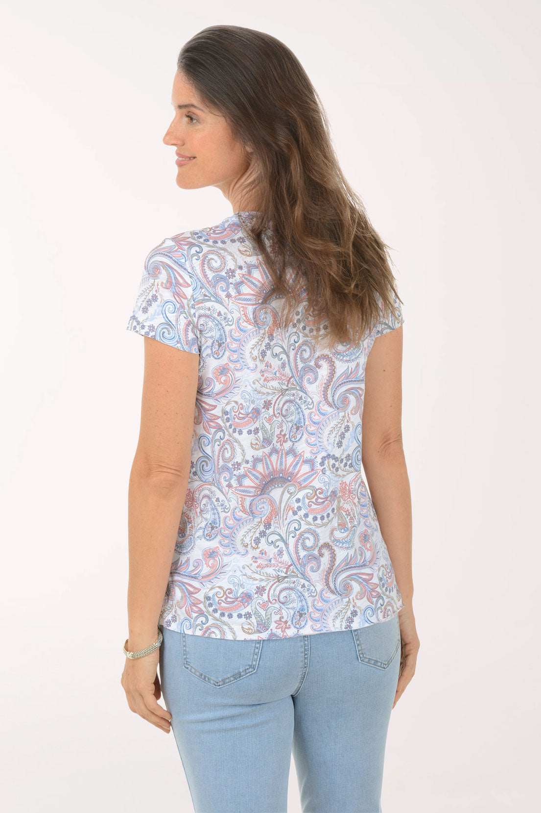 Woman wearing a patterned shirt and light blue jeans on a white background