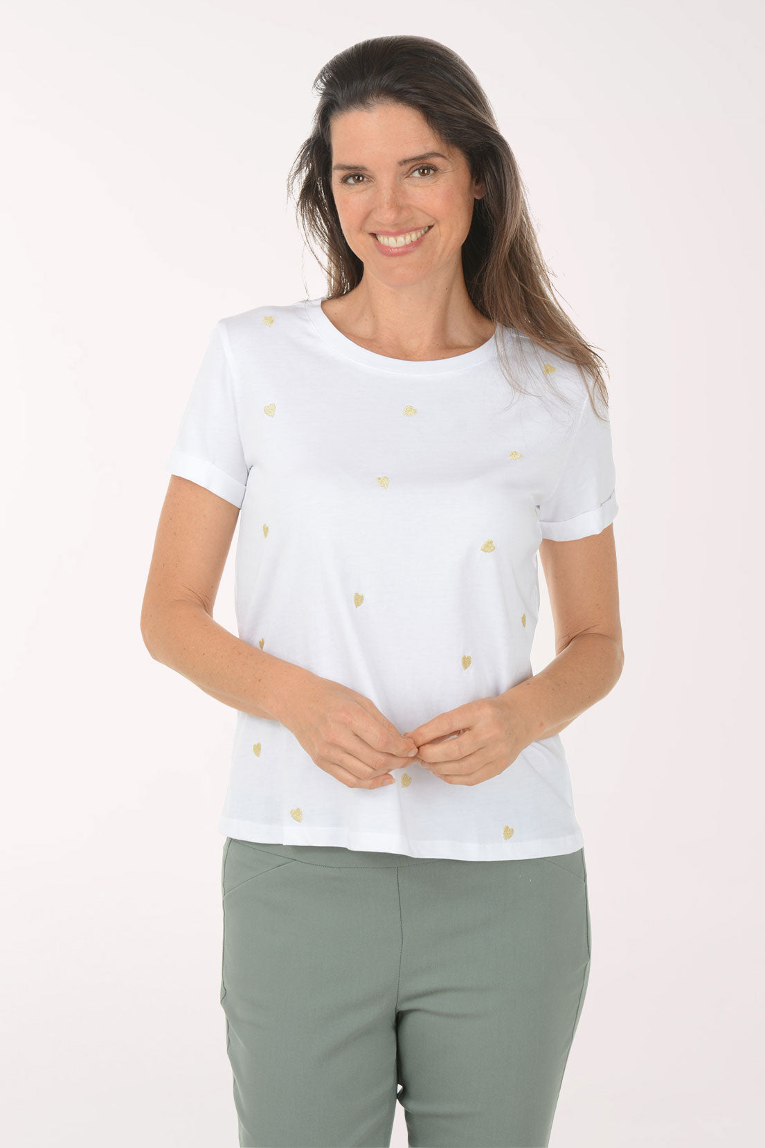Woman wearing a white t-shirt with a heart pattern and green pants on a white background