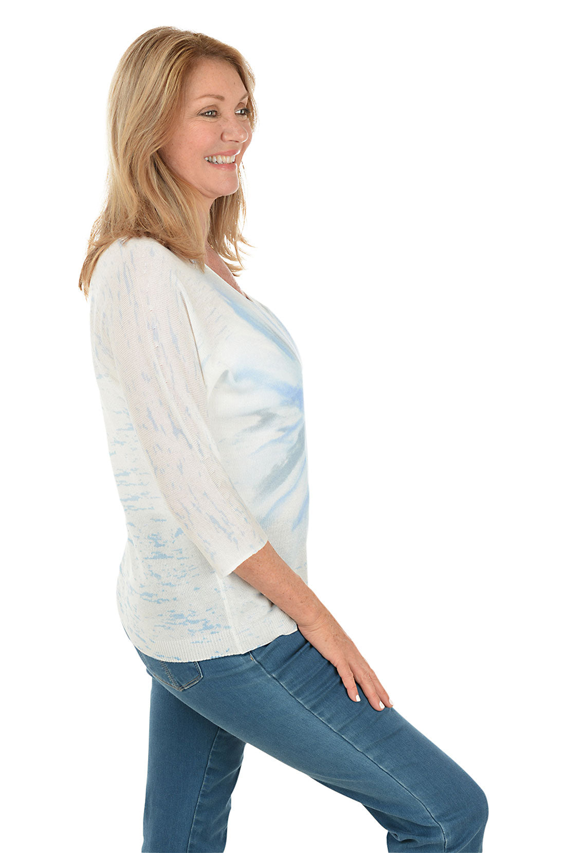 A woman wearing a tie-dye dolman sleeve sweater with a V-neck in blue and white. Side shot.