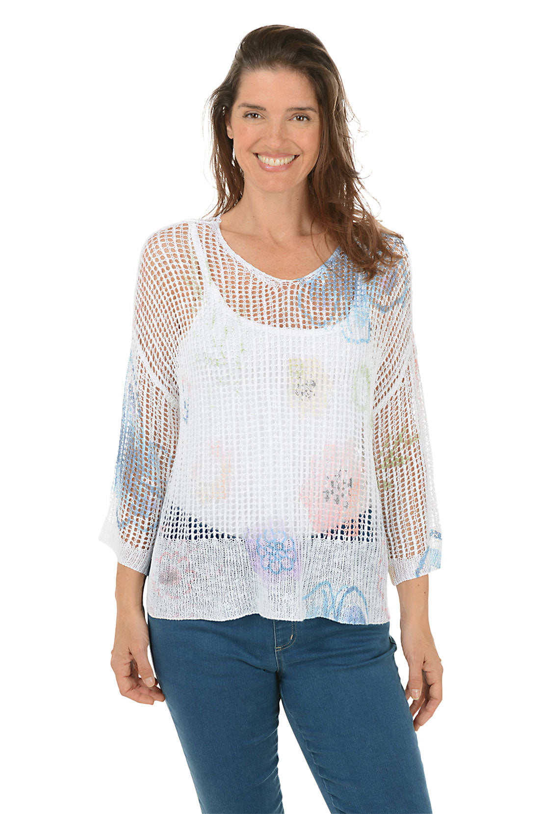 A woman wearing a floral watercolor crochet high-low sweater in white, with 3/4 dolman sleeves and a high-low hemline.