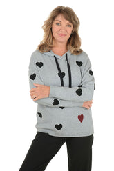 Woman wearing a gray hoodie with black heart patterns on a white background.