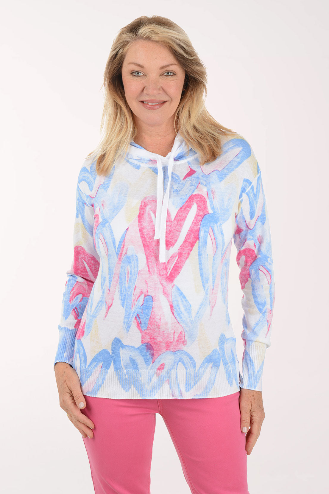 Woman wearing a colorful hoodie and pink pants on a white background