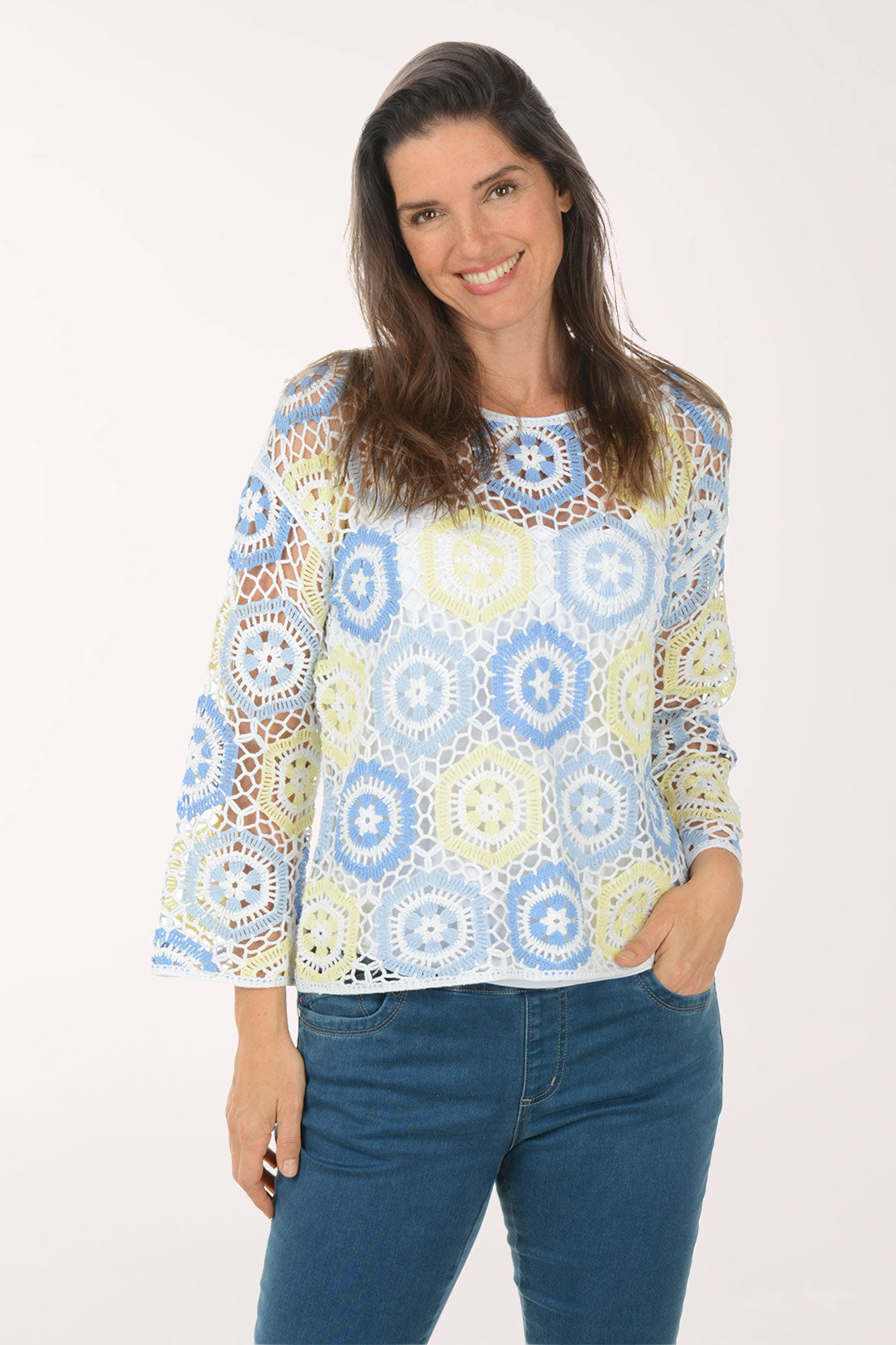 Woman wearing a colorful patterned top and blue jeans on a white background
