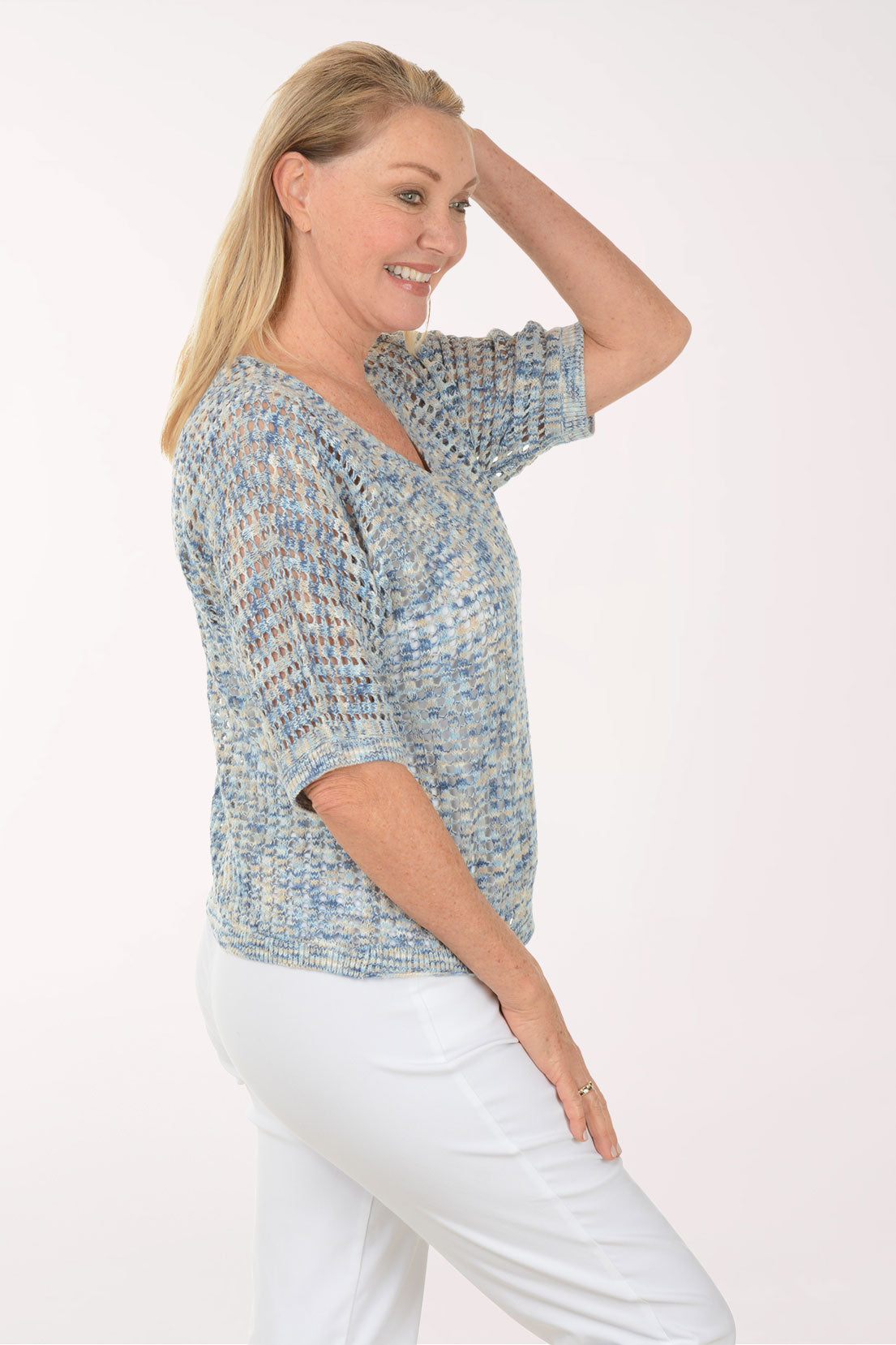 Woman wearing a textured blue top and white pants on a white background
