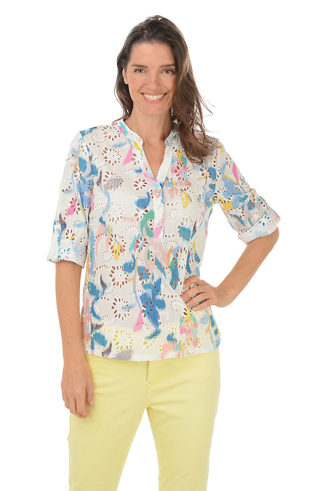 A woman wearing a multicolored floral eyelet lace cotton blouse with a mandarin collar and 3/4 sleeves, paired with yellow pants.