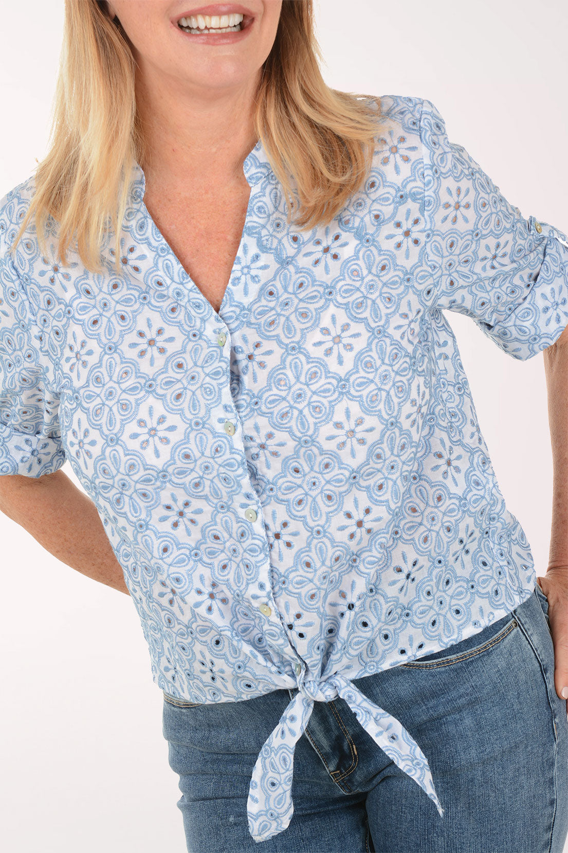 Woman wearing a light blue patterned shirt with short sleeves on a white background