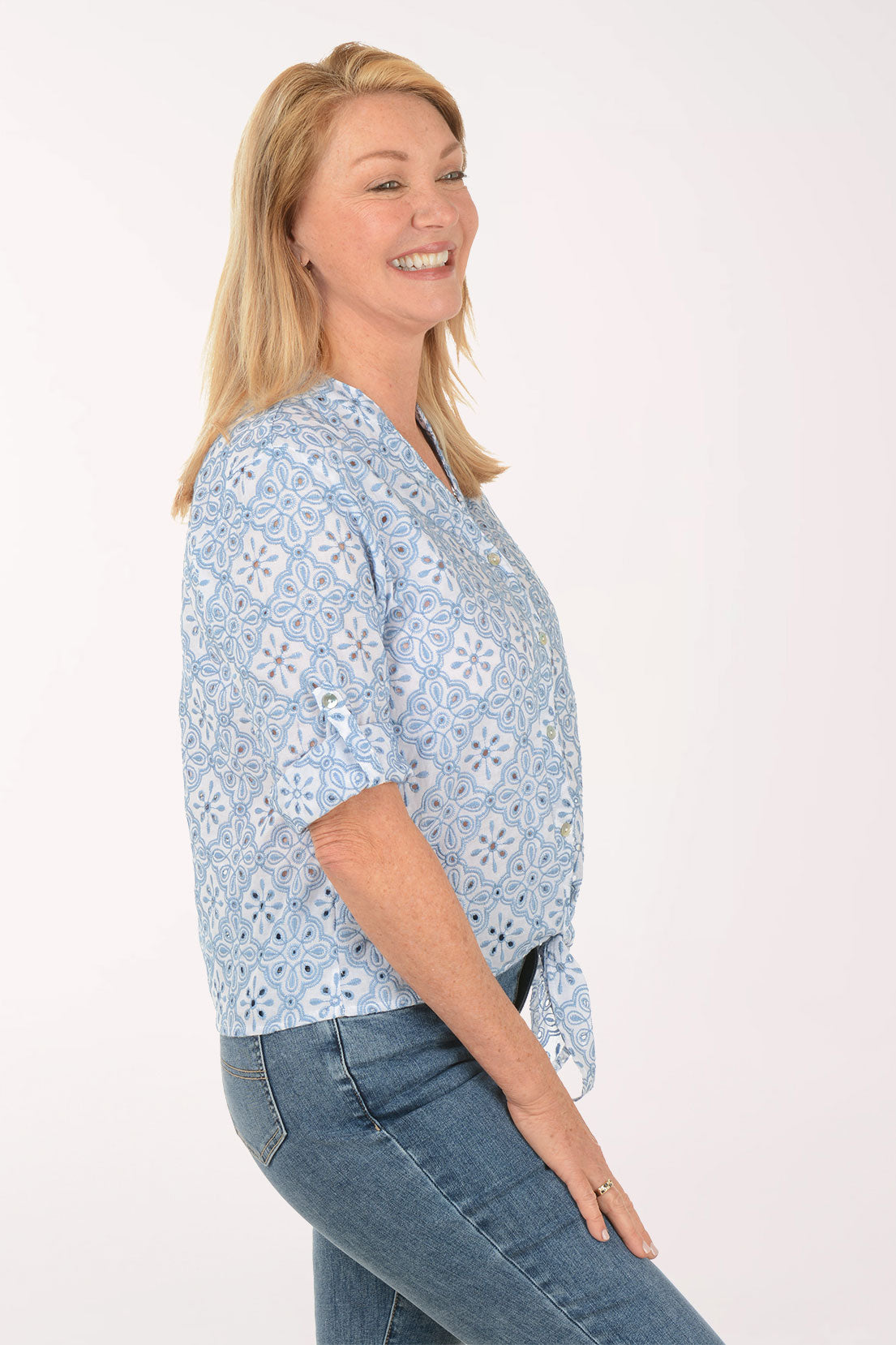 Woman wearing a light blue patterned shirt with short sleeves on a white background