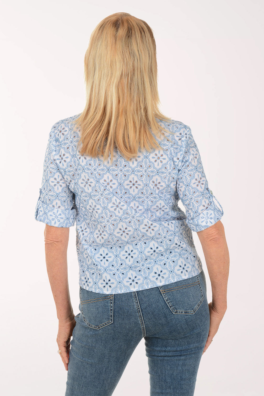 Woman wearing a light blue patterned shirt with short sleeves on a white background