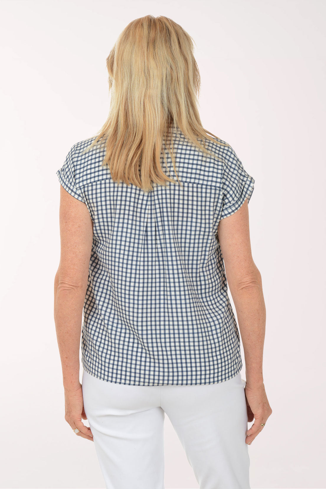Woman wearing a black and white checkered shirt with white pants on a white background