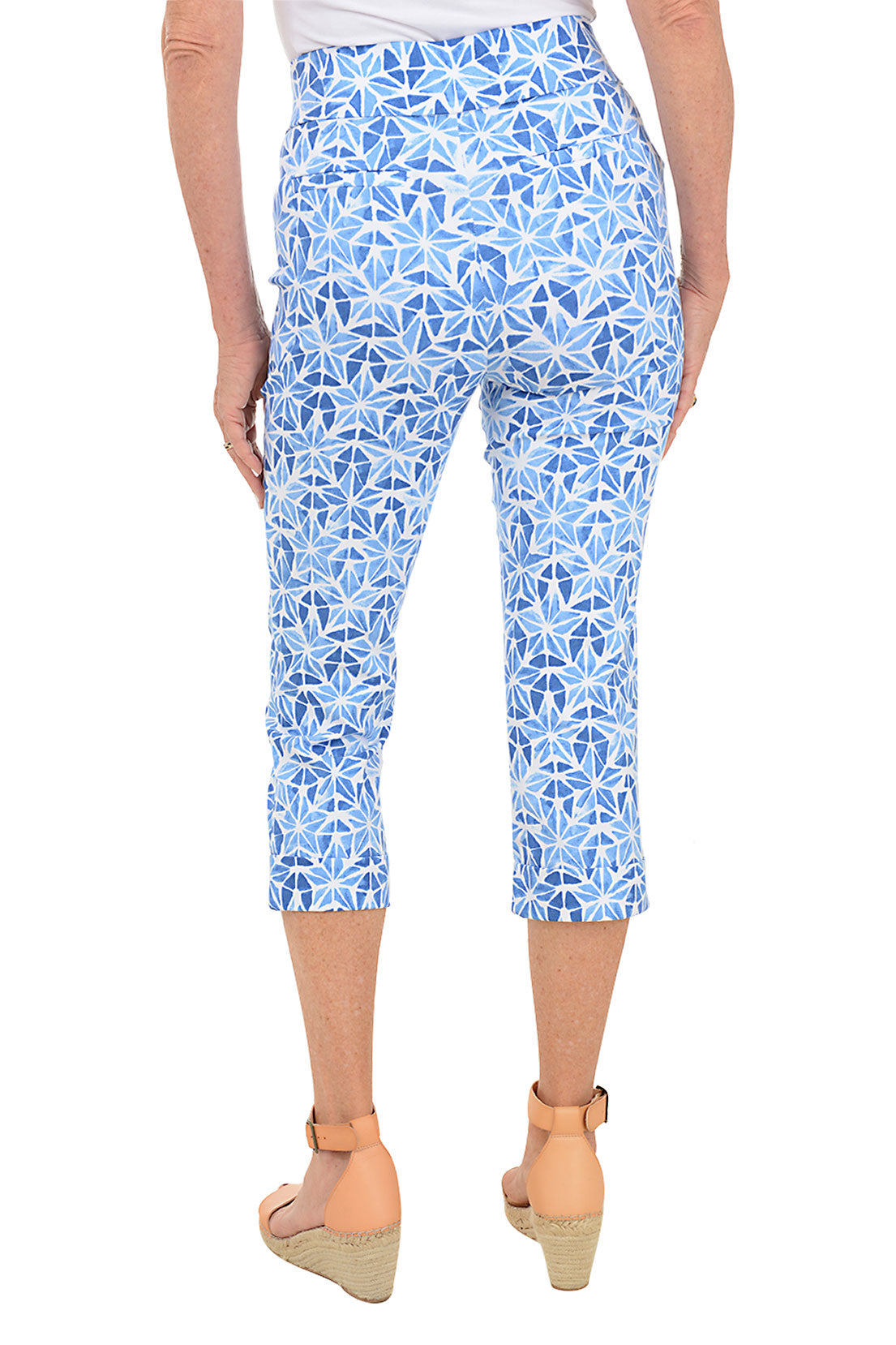 A pair of blue capri pants with a star print, featuring a wide stretch waistband, faux front and back pockets, and a cuffed hem. Back shot.