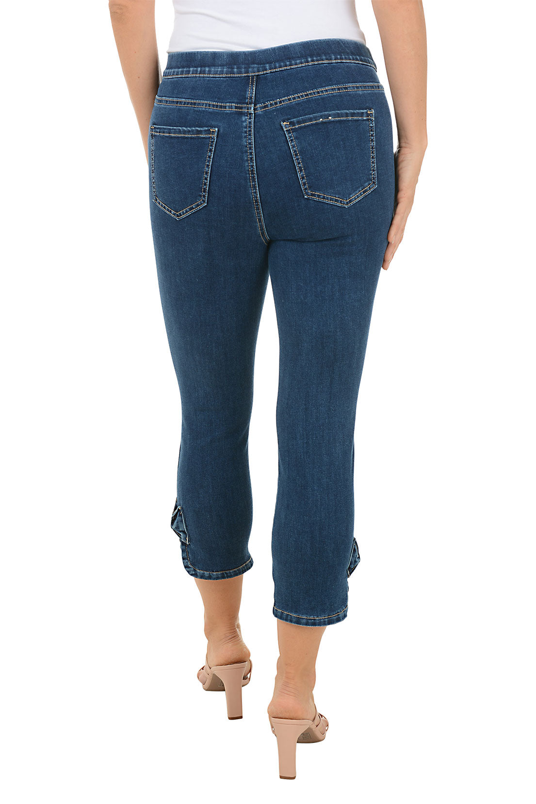 A person wearing a blue denim capri pant with an elasticized waistband and a bow detail on the hem. The person is standing and posing for the camera. Back shot.